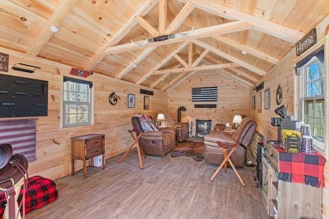 interior space with wooden walls, lofted ceiling with beams, wooden ceiling, hardwood / wood-style floors, and a wood stove