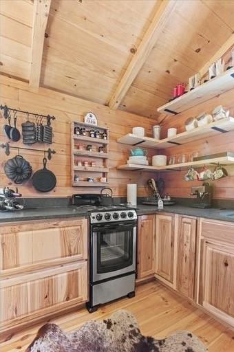 kitchen with beam ceiling, stainless steel range, light hardwood / wood-style flooring, wooden walls, and wood ceiling