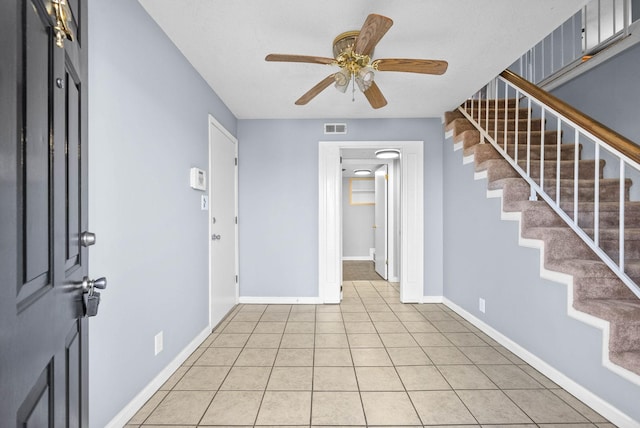 entrance foyer with light tile patterned floors, visible vents, a ceiling fan, baseboards, and stairs