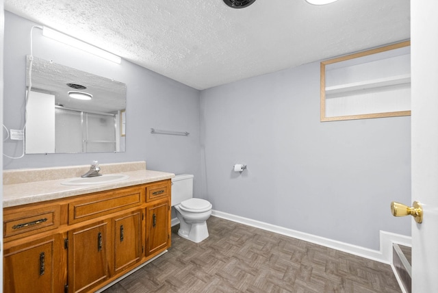 bathroom with a textured ceiling, toilet, vanity, baseboards, and walk in shower