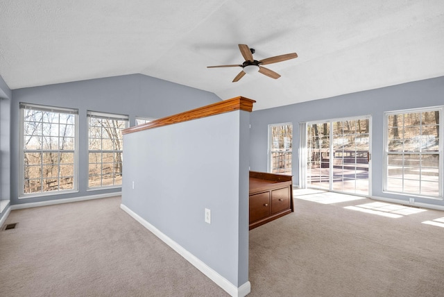 empty room featuring carpet, ceiling fan, lofted ceiling, and baseboards