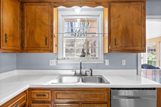 kitchen featuring dishwasher, light countertops, a sink, and brown cabinets