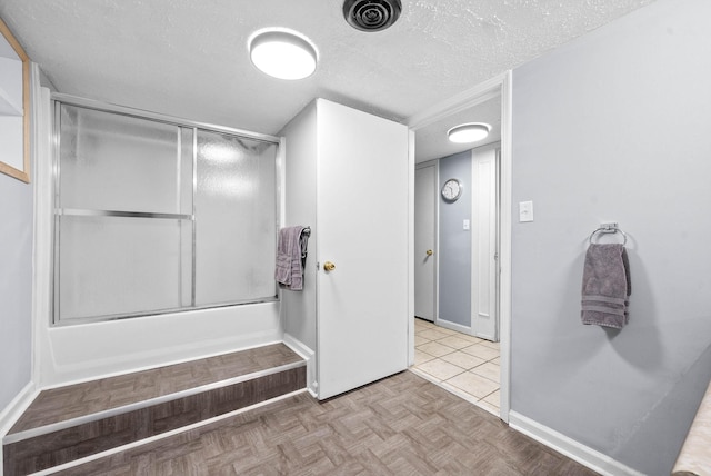 bathroom with visible vents, a textured ceiling, baseboards, and bath / shower combo with glass door