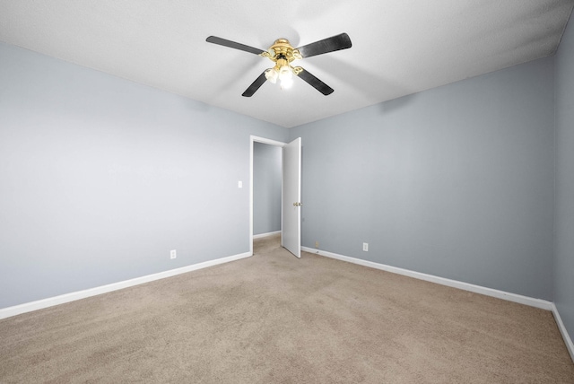 carpeted spare room featuring ceiling fan and baseboards