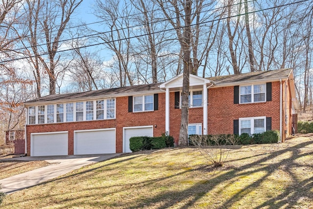 raised ranch with a garage, a front yard, brick siding, and driveway