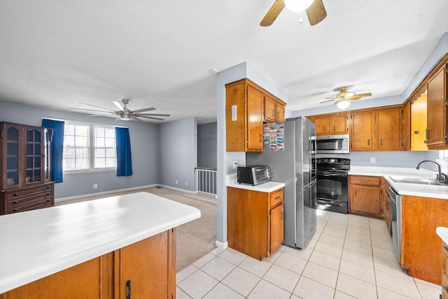 kitchen with stainless steel appliances, brown cabinetry, a sink, and light tile patterned floors