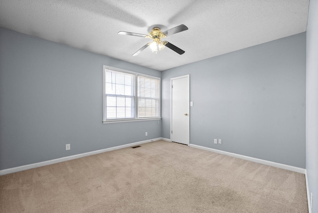 unfurnished room with a textured ceiling, light carpet, visible vents, a ceiling fan, and baseboards