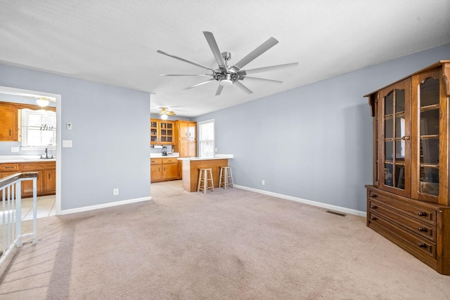 unfurnished living room with a healthy amount of sunlight, light carpet, a sink, and baseboards