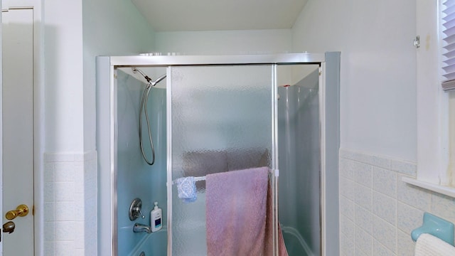 bathroom with enclosed tub / shower combo and tile walls