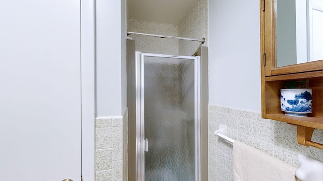 bathroom featuring tile walls and a shower with shower door