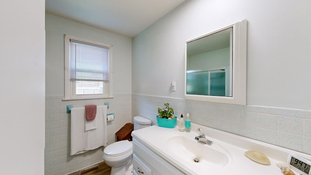 bathroom with an enclosed shower, vanity, hardwood / wood-style flooring, tile walls, and toilet