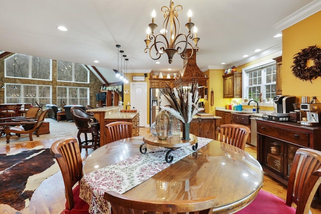 dining area featuring ornamental molding, sink, an inviting chandelier, light hardwood / wood-style floors, and lofted ceiling