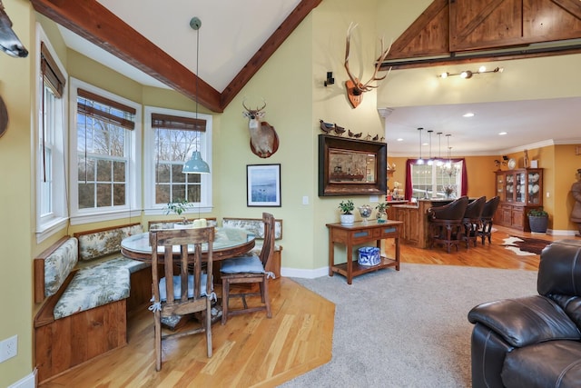 carpeted dining room featuring vaulted ceiling with beams, breakfast area, and ornamental molding