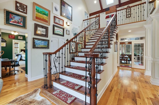 staircase featuring decorative columns, french doors, high vaulted ceiling, and wood-type flooring