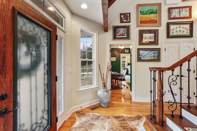 entryway with beam ceiling, light wood-type flooring, a wealth of natural light, and ceiling fan