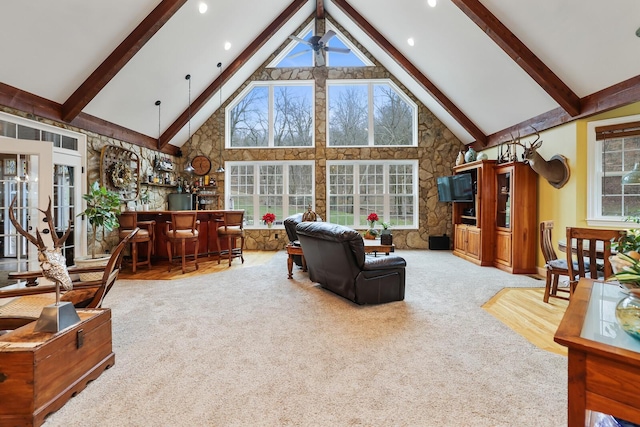 carpeted living room with ceiling fan, beamed ceiling, and high vaulted ceiling