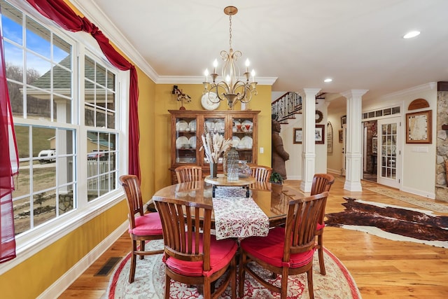 dining area featuring a chandelier, light wood-type flooring, ornate columns, and ornamental molding