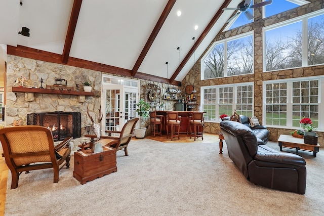 carpeted living room featuring ceiling fan, beam ceiling, high vaulted ceiling, a fireplace, and bar area