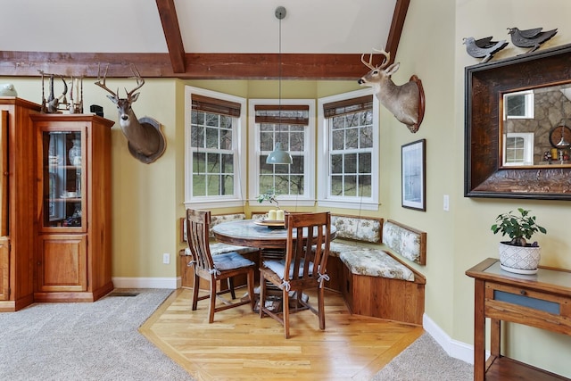 carpeted dining room featuring breakfast area and beamed ceiling