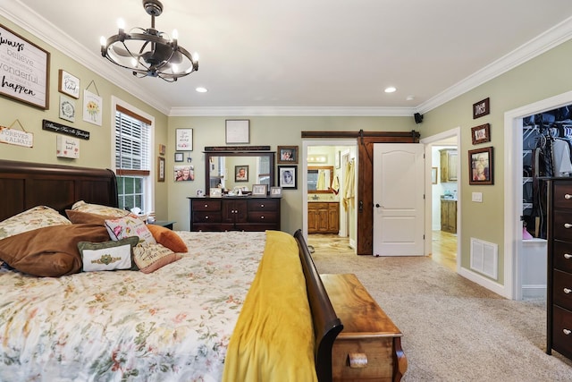 carpeted bedroom with connected bathroom, a barn door, a notable chandelier, a walk in closet, and ornamental molding