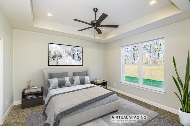 carpeted bedroom with a tray ceiling and ceiling fan