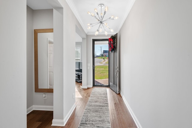 foyer with hardwood / wood-style floors, ornamental molding, and a chandelier