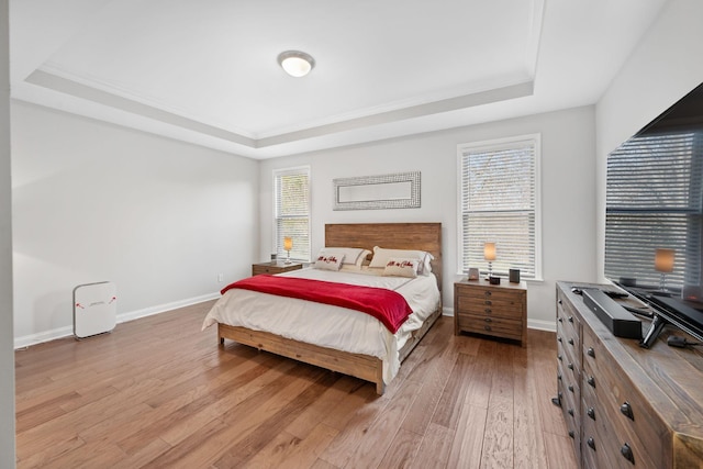 bedroom with light hardwood / wood-style floors and a tray ceiling