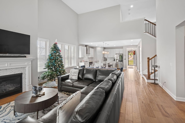 living room with a healthy amount of sunlight, light wood-type flooring, a fireplace, and a high ceiling