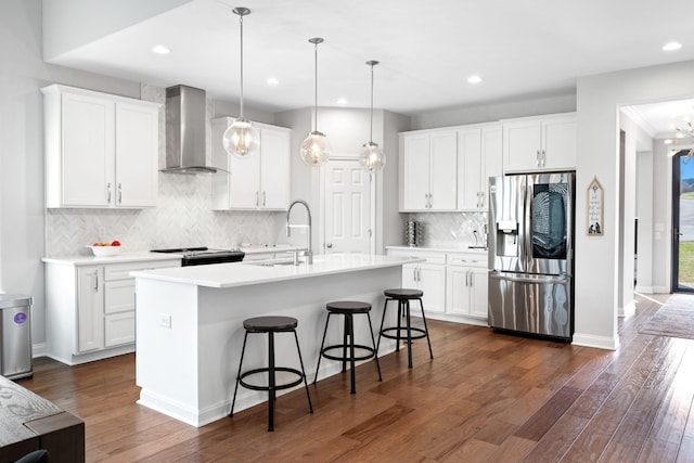 kitchen featuring white cabinets, wall chimney range hood, and appliances with stainless steel finishes