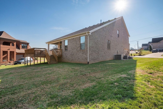 rear view of house with a deck, a yard, and central AC