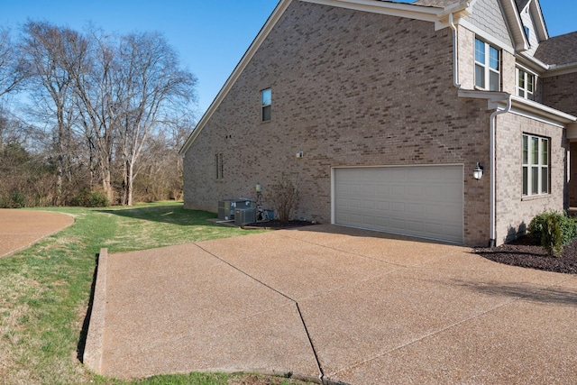 view of side of home with a yard, cooling unit, and a garage