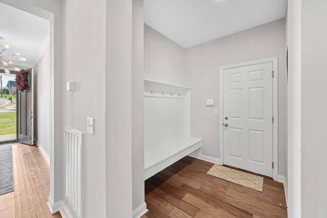 mudroom featuring a chandelier, hardwood / wood-style floors, and ornamental molding