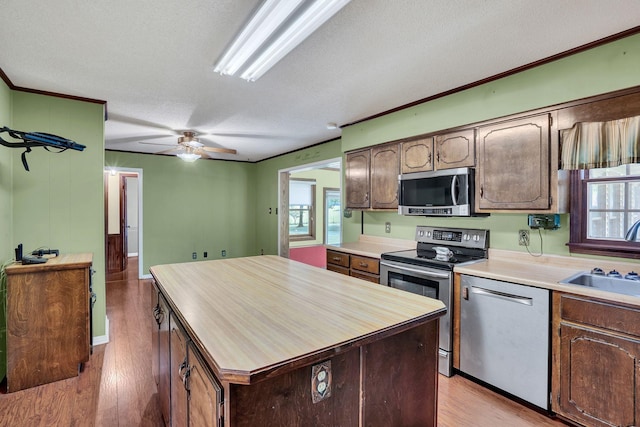 kitchen featuring a center island, sink, a textured ceiling, appliances with stainless steel finishes, and light hardwood / wood-style floors