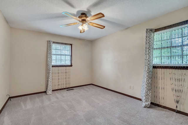 carpeted spare room featuring ceiling fan and a textured ceiling