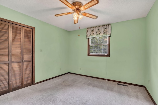 unfurnished bedroom featuring ceiling fan, a closet, light carpet, and a textured ceiling