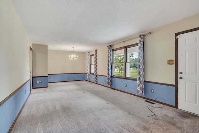 unfurnished room with a chandelier, a textured ceiling, and carpet floors