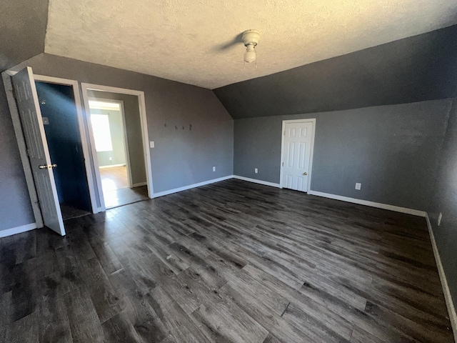 bonus room featuring dark hardwood / wood-style flooring, a textured ceiling, and vaulted ceiling