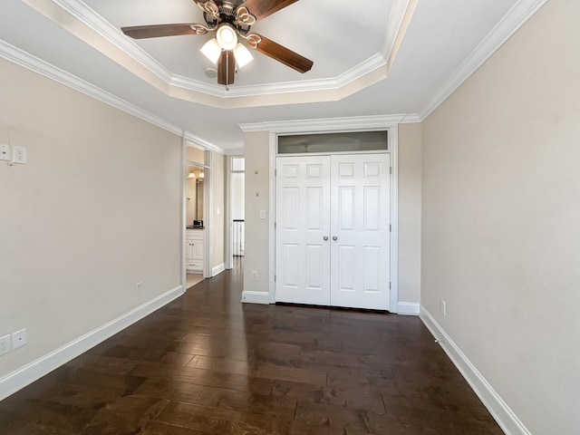 unfurnished bedroom with dark wood-type flooring, a tray ceiling, ceiling fan, and crown molding