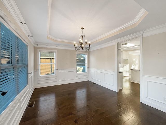 unfurnished dining area featuring a chandelier, a tray ceiling, dark hardwood / wood-style floors, and ornamental molding