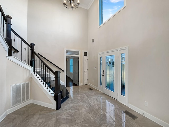 entrance foyer with a healthy amount of sunlight, a chandelier, a high ceiling, and ornamental molding