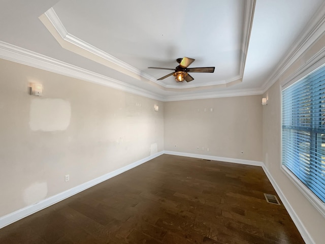 unfurnished room featuring a tray ceiling, ceiling fan, crown molding, and dark wood-type flooring