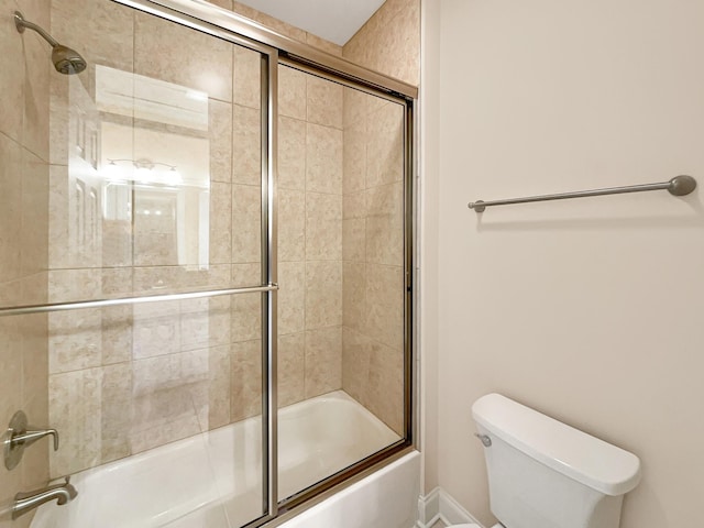 bathroom with toilet and combined bath / shower with glass door