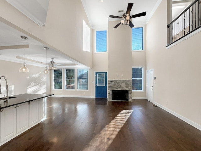 unfurnished living room with ceiling fan, dark hardwood / wood-style flooring, ornamental molding, and a fireplace