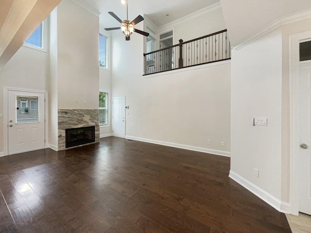 unfurnished living room with a high ceiling, a fireplace, baseboards, dark wood-style flooring, and ceiling fan