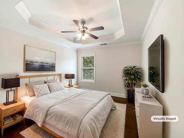 bedroom with ornamental molding, dark wood-type flooring, a raised ceiling, and visible vents