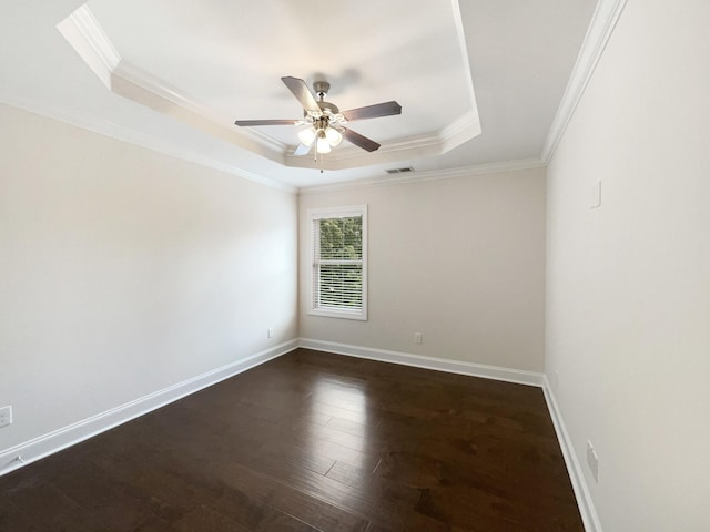spare room featuring ornamental molding, visible vents, a ceiling fan, dark wood-style floors, and a tray ceiling