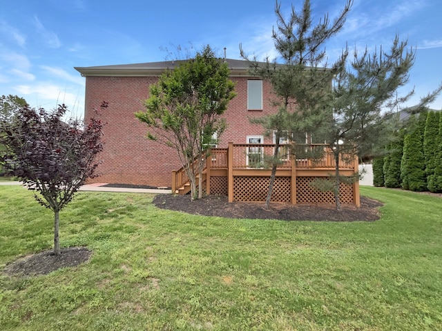 rear view of house with a yard, a deck, brick siding, and stairway