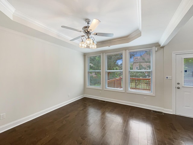 unfurnished room featuring baseboards, dark wood finished floors, ceiling fan, crown molding, and a raised ceiling