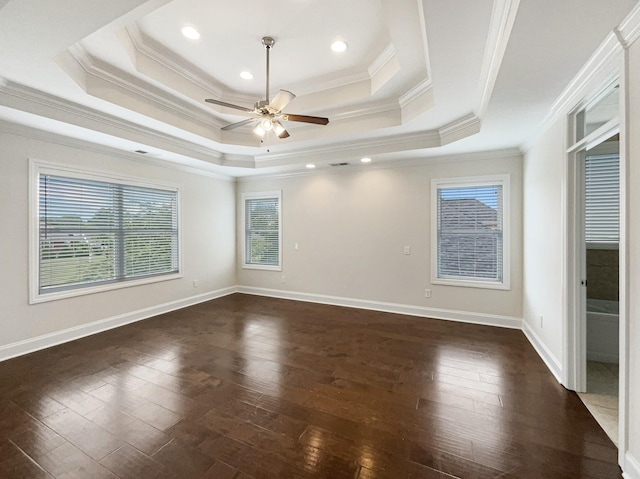 unfurnished bedroom with multiple windows, dark wood finished floors, a raised ceiling, and ornamental molding