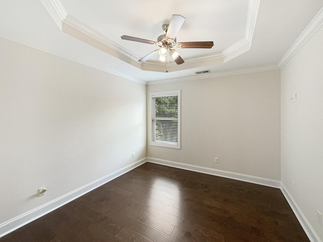 empty room with visible vents, crown molding, dark wood-style flooring, a ceiling fan, and a raised ceiling